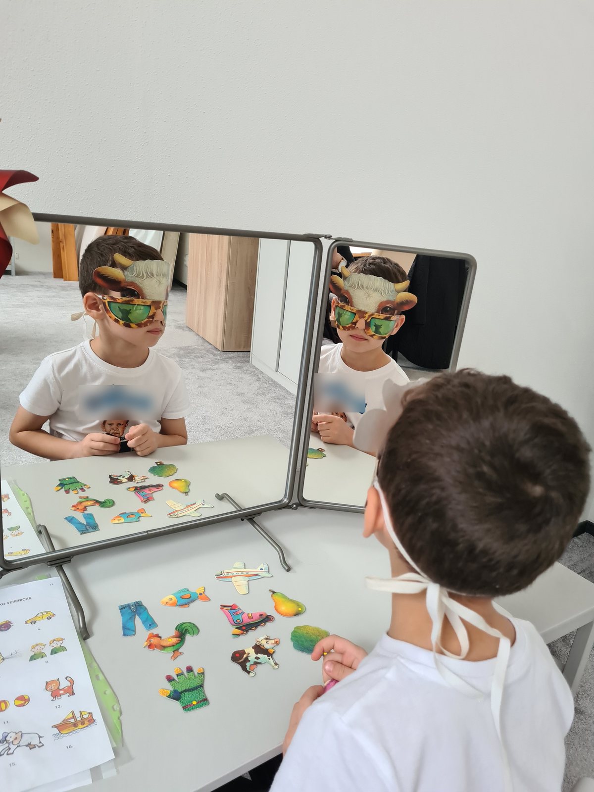 Dieťa s maskou pozoruje svoj odraz v zrkadle pri logopedickom cvičení